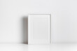Vertical blank frame mockup in white minimalistic interior for artwork, print or photo presentation