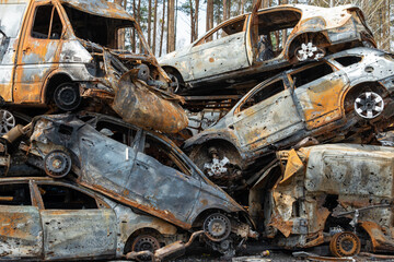 Many shot and destroyed cars of civilians at the car graveyard in Irpin, Ukraine. War in Ukraine. Car accident.