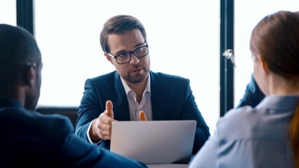 Poster - Businessman in suit talking in meeting with team using computer