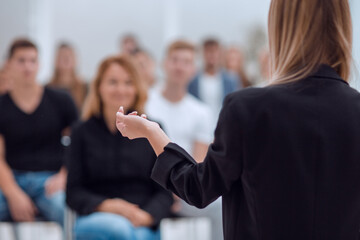 Canvas Print - rear view. young woman doing a report for a group of young people