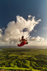 Young beautiful female model having fun on the swings at Montaña Redonda during epic sunrise 