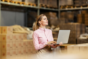 A food industry worker checking on shipment on the laptop in warehouse.