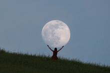 Full Moon Portrait At Blue Hour With A Girl Holding The Moon Above Her Head, Emilia Romagna