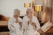 © zinkevych - A senior couple in white robes having coffee and talking