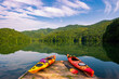 Kayaks on dock with mountains reflecting on calm water in the background