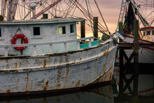 An Old Wooden Shrimp Boat At Port With Sunset In Background At South Carolina's Port Royal