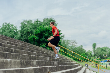 Wall Mural - Fit male athlete performing stairs workout, running up climbing stairs performing outdoor track cardio..