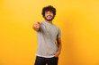 © Vadim Pastuh - Smiling young indian man with curly hairstyle pointing finger at you standing isolated on yellow background, cheerful teenage guy indicating at the camera