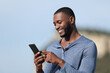 © PheelingsMedia - Happy man with black skin using smart phone outside