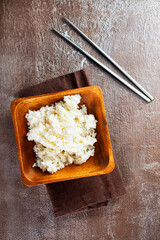 Wall Mural - Bowl of boiled rice and sticks on dark table