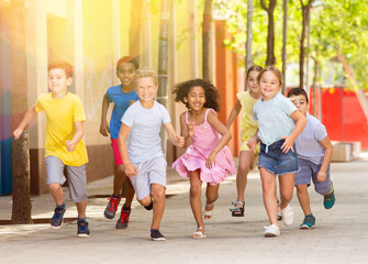 Wall Mural - Happy children running in race and laughing outdoors at sunny day