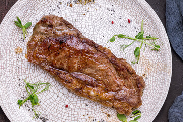 Sticker - juicy Striploin Steak on grey plate on dark stone table top view