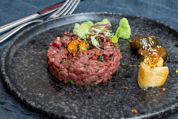 Wall Mural - Tartare from beef with egg on black plate side view