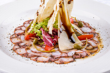 Wall Mural - carpaccio of octopus with parmesan and vegetables on a white plate macro close up