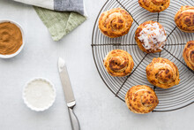 Top Down View Of Cinnamon Buns On A Cooling Rack Served With Cream Cheese Icing.