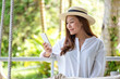 Portrait image of a beautiful young asian woman in white shirt with hat holding and using mobile phone
