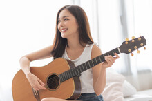 Portrait Of Pretty Korean Woman Is Playing Acoustic Guitar, Smiling Face.