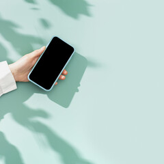 mock up phone with black blank screen in female hand, white shirt sleeve, minimal flatlay on pastel 
