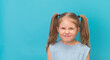 Angry furious child grimacing make face over blue background.