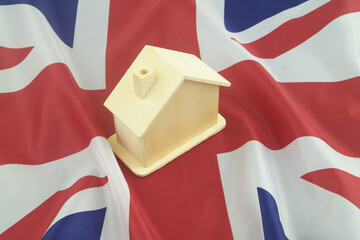 Wooden house model on UK flag close-up. Real estate in United Kingdom concept.	