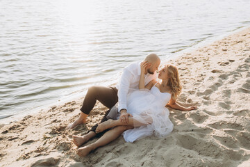 Wall Mural - Wedding photosession at sunset of a beautiful couple, the bride in a white dress, and the groom in a white shirt and black trousers