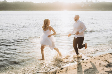 Wall Mural - Wedding photosession at sunset of a beautiful couple, the bride in a white dress, and the groom in a white shirt and black trousers