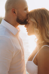 Wall Mural - Wedding photosession at sunset of a beautiful couple, the bride in a white dress, and the groom in a white shirt and black trousers