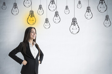 Poster - Portrait of attractive pensive young european businesswoman standing on concrete wall background with glowing drawn light bulb sketch and mock up place. Idea and creativity concept.