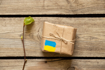 Wall Mural - A box with a painted yellow-blue flag of Ukraine on a wooden table, humanitarian aid for Ukraine, postal parcel