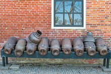 Traditional Vintage Milk Canisters In Front Of An Old Farmhouse In The Agricultural Province Of Groningen, The Netherlands. Reflection Of Trees In Window.