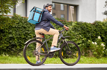 Poster - food shipping, transportation and people concept - happy smiling delivery man in bike helmet with thermal insulated bag riding bicycle on city street