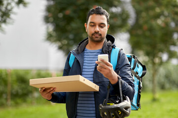 Wall Mural - food shipping, profession and people concept - delivery man with thermal insulated bag and takeaway pizza box using smartphone on city street