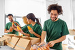 © Syda Productions - charity, donation and volunteering concept - international group of happy smiling volunteers packing food and drinks in boxes at distribution or refugee assistance center