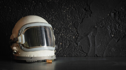 concept of astronaut helmet on the table on the black wall background with copy space.