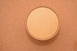 A paper cup covered with a cardboard lid. Top view on a brown background