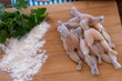 fresh raw frog legs with parsley and flour on wooden board, French cuisine 