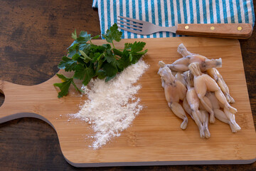 Wall Mural - fresh raw frog legs with parsley and flour on wooden board, French cuisine 