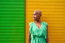 Young Woman With Short Blond Hair Standing In Front Of Green And Yellow Wall