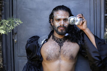 Eccentric long haired man with tons of glitter in disco ball party look