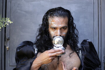 Eccentric long haired man with tons of glitter in disco ball party look