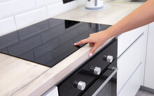 Modern induction hob in the kitchen. A woman's hand sets the heating power of the burner, ceramic