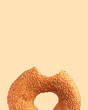 Fresh bitten round wheat bagel with sesame seeds isolated on beige background. Crispy bread, healthy organic food, traditional pastries, bakery product. Breakfast bagel, element for advertising 
