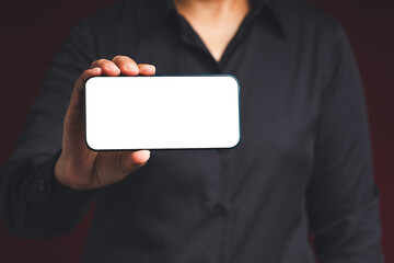 Wall Mural - hand holding a blank screen smartphone while standing on a black background