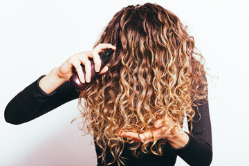 Wall Mural - Young woman holding her curly brown hair