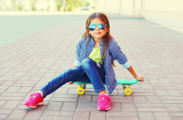 Wall Mural - Portrait of little girl child posing with skateboard in the city