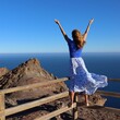 Swobodna kobieta ubrana w długą spódnicę w wietrzny dzień ciesząca się pięknym widokiem oceanu na wyspie Fuerteventura