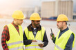 © PintoArt - Multiracial container workers using walkie-talkie and tablet to check work on container loading, import and export concept.