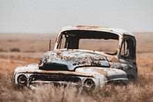 Closeup Of An Old Abandoned Rusty Car In A Field Of Dried Grass