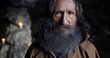 © procinemastock - Portrait of senior sage man in cassock and with gray hair standing in rocky cave with candles and looking at camera