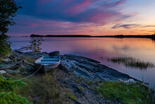 View Of The Sunset Over The Bay In Brusnwick Maine With Boat On The Rocks